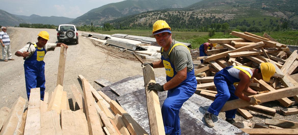 مردان بر روی ساخت یک جاده جدید در آلبانی کار می کنند.